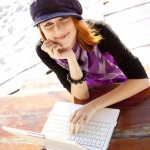 Portrait of red-haired girl with laptop at beach.